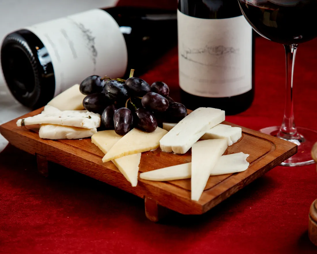 Vinhos tintos servidos com tábua de queijos e uvas